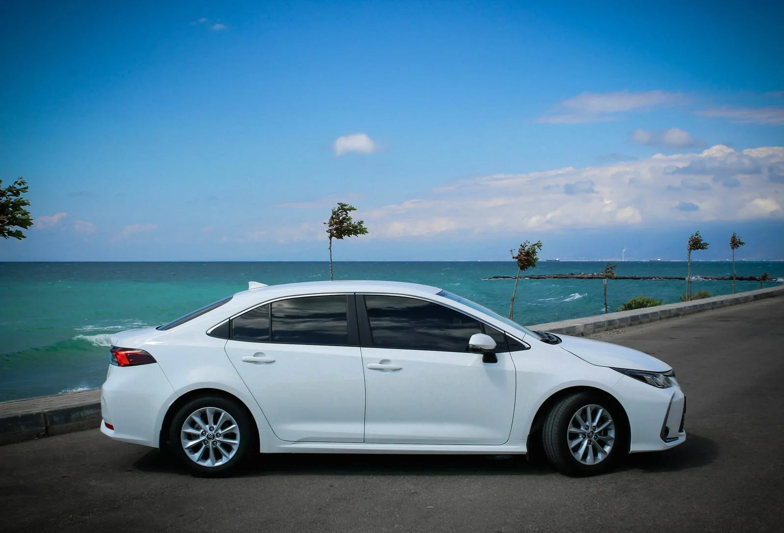 Biała Toyota Corolla sedan nad morzem, widok z boku