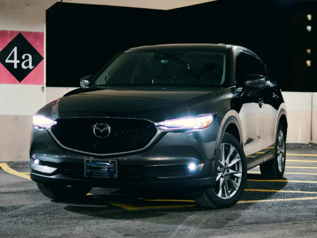 Grafitowa Mazda CX-5 z włączonymi światłami